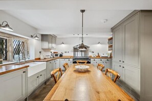A modern kitchen with a wooden dining table, grey cabinets, and stainless steel appliances.