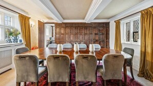 Una sala conferenze con un lungo tavolo in legno, sei sedie e un pannello decorativo a parete in legno.