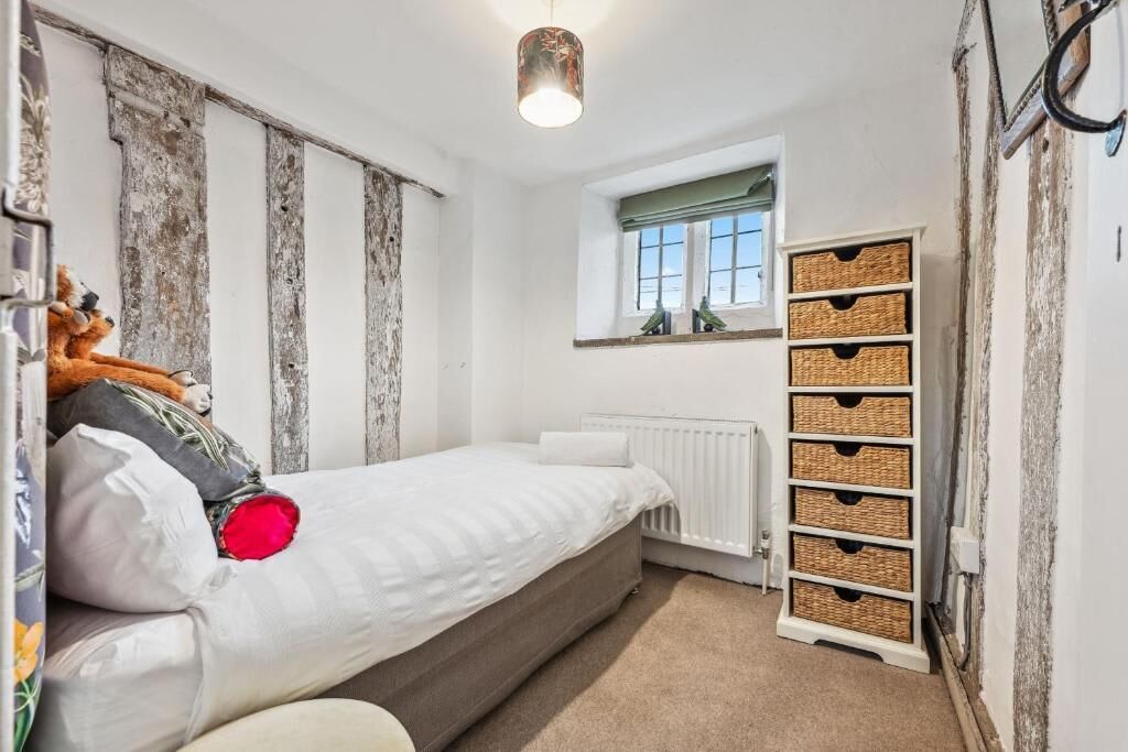 Ein Schlafzimmer mit Bett, Heizkörper, Fenster mit Blick und einer an der Wand befestigten Aufbewahrungsbox.