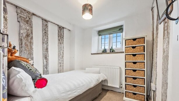 Una camera da letto con un letto, un termosifone, una finestra con vista e un mobile contenitore a parete.