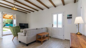 A modern living room with a sofa, a wooden side table, a television, and a lamp.