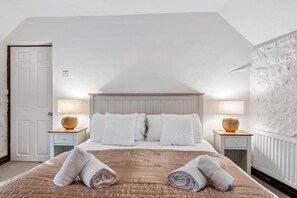A bedroom with a bed, two bedside tables with lamps, a door, and a textured wall.