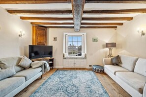 Ein Wohnzimmer mit zwei Sofas, einem Fernseher, einem Fenster und einem gemusterten Teppich.
