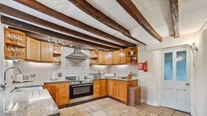 Una cocina con armarios de madera, horno empotrado, lavaplatos y salpicadero de azulejos.