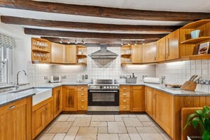 Una cocina con armarios de madera, estufa de acero inoxidable y salpicadero de azulejos.