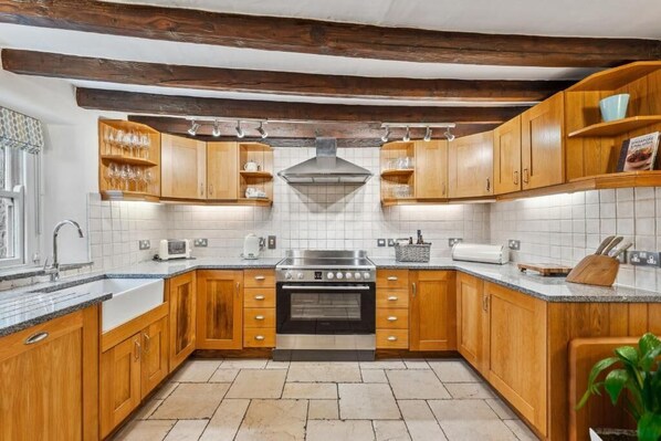 Une cuisine avec des meubles en bois, une cuisinière en acier inoxydable et un dosseret carrelé.