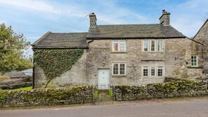 A stone house with a white door, a stone wall with ivy, and a stone fence. - Host & Stay | Ivy Farm House - Wetton (Ashbourne)