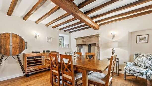 Un comedor con una mesa y sillas de madera, un armario de madera y una chimenea.