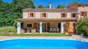 A stone house with a swimming pool, outdoor furniture, and a garden.