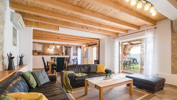 A cozy living room with a sofa, a coffee table, and a view of the kitchen and outdoor patio.