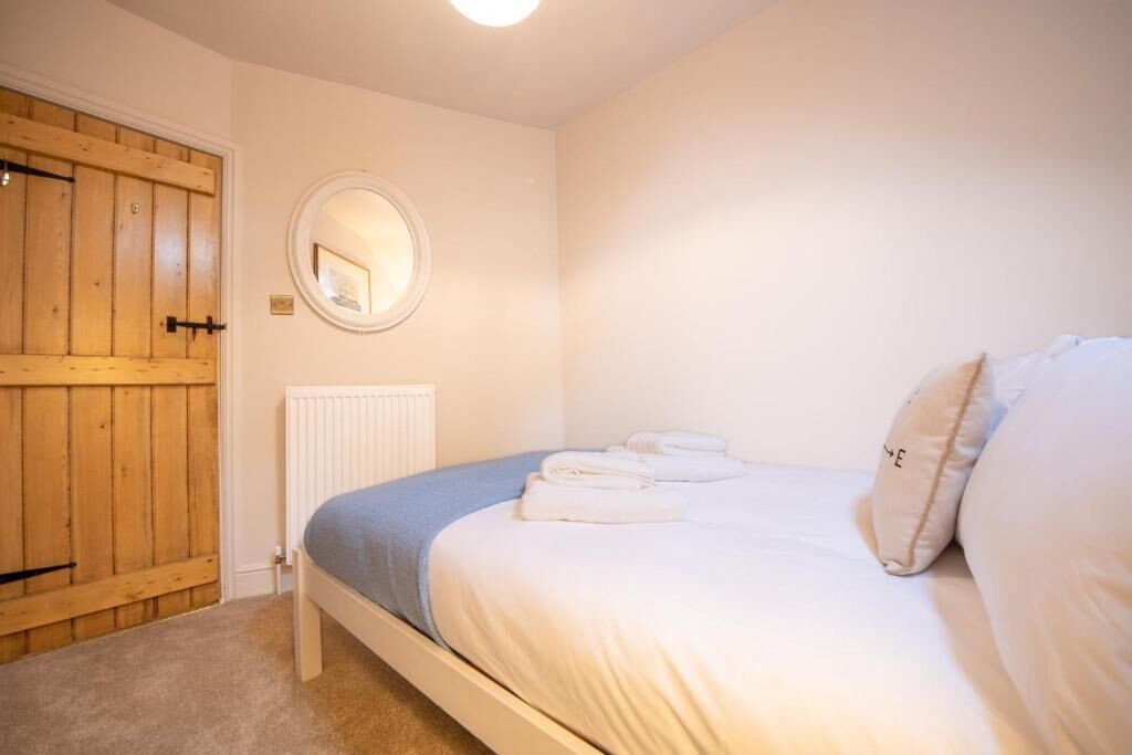 Ein Schlafzimmer mit einem Bett, einem runden Spiegel, einer Holztür und einer Heizung.