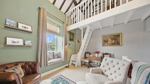 En hyggelig stue med højt til loftet, en trappe og et spiseområde.