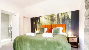 A bedroom with a bed, a nightstand, a wall-mounted lamp, and a bathroom with a shower and toilet. - Host & Stay | Staffordshire Knot (Sheen)
