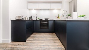 A modern kitchen with a central island, built-in oven, and a wooden floor. - Host & Stay | Staffordshire Knot (Sheen)