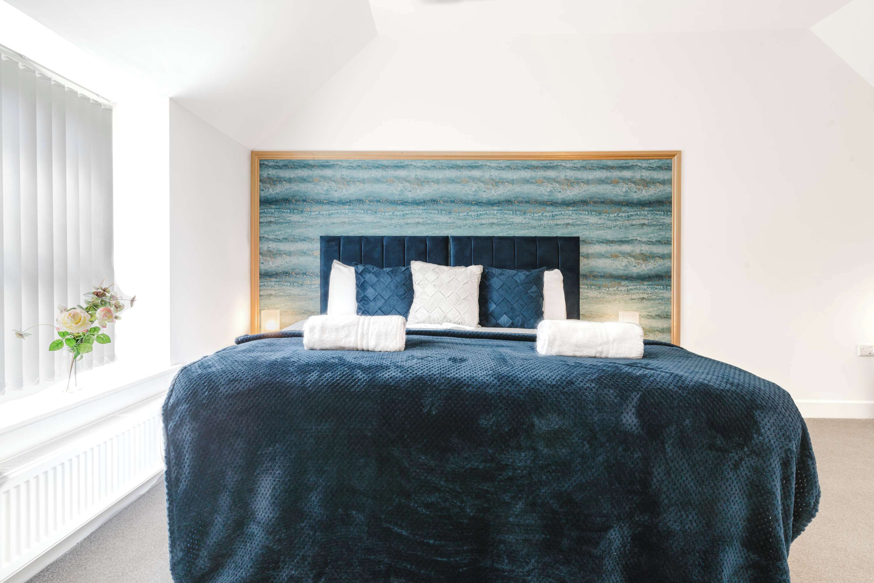 Une chambre à coucher avec un grand lit, une tête de lit et une œuvre d’art murale.