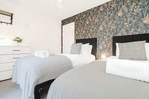 Een hotelkamer met twee bedden, een dressoir en bloemenbehang.