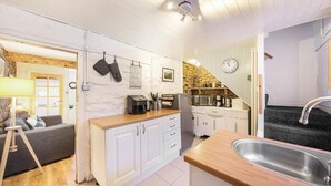 A compact kitchen with white cabinets, a wooden countertop, and a stainless steel sink. - Host & Stay | Batemill Cottage (Birch Vale)