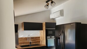 A modern kitchen with a black refrigerator, built-in oven, microwave, and a wooden countertop. - Villa with pool near Uzès (Saint-Laurent-la-Vernède)