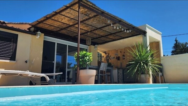 A swimming pool with a covered patio area, a chair, and potted plants. - Villa with pool near Uzès (Saint-Laurent-la-Vernède)