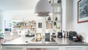 Una cocina moderna con una isla central, electrodomésticos de acero inoxidable y una lámpara colgante grande.