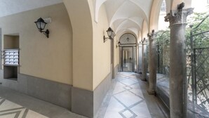 Un pasillo con techos abovedados, suelo de baldosas y columnas.