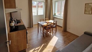 A compact living space with a kitchenette, dining area, and a sofa. - Apartmá Gabriela (Brno)