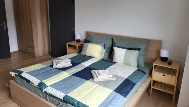 A bedroom with a large bed, two bedside tables, a wardrobe, and a door. - Apartmá Gabriela (Brno)