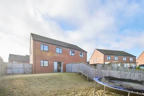 A residential area with a brick house, a wooden fence, and a trampoline in the yard. - Host & Stay | Falstaff Crescent (Sheffield)