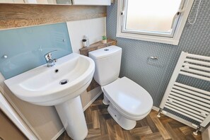 Casa de banho com lavatório branco, sanita e janela.