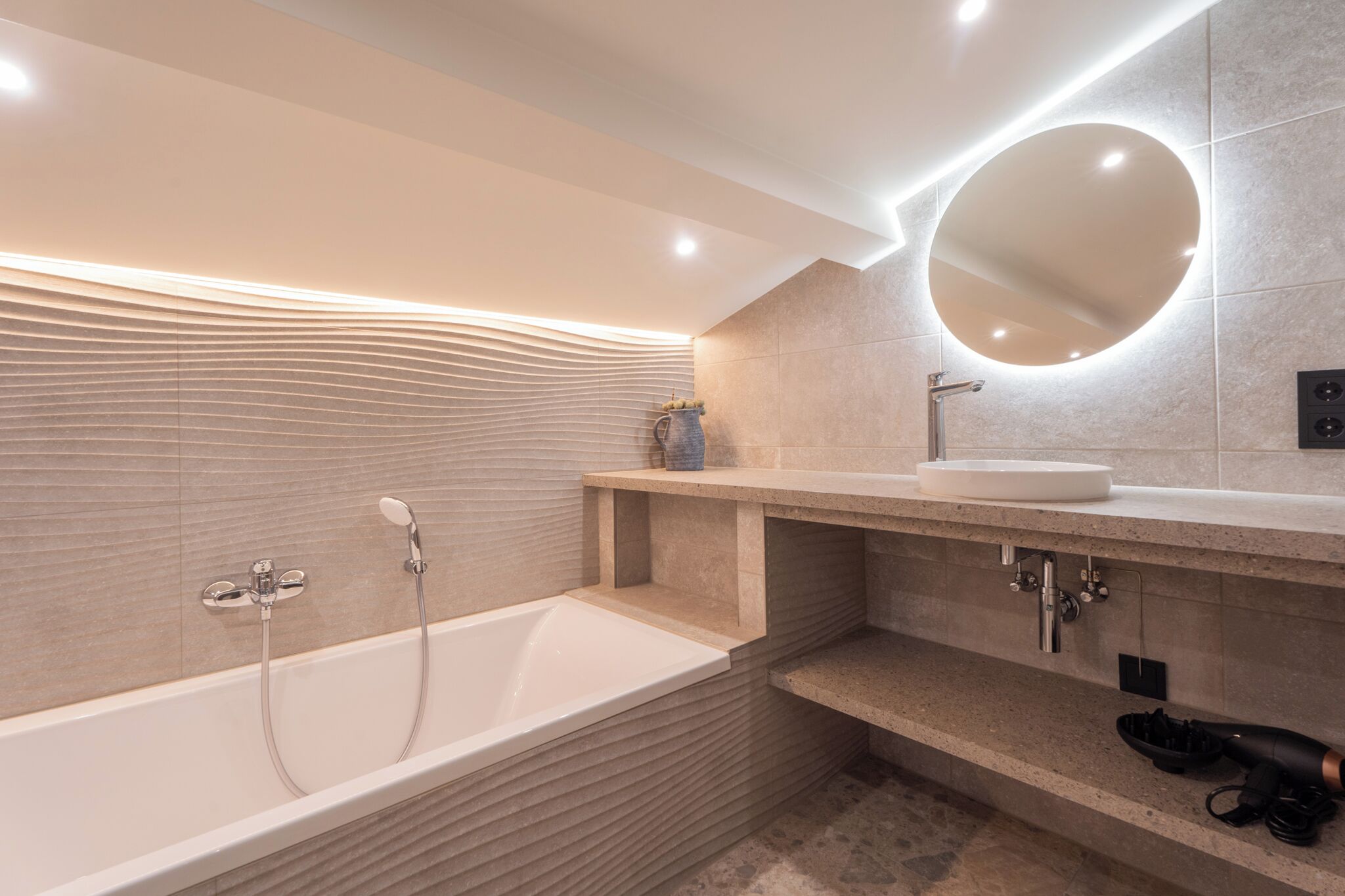 Une salle de bain moderne avec une baignoire sur pieds, un miroir rond et un lavabo encastré.