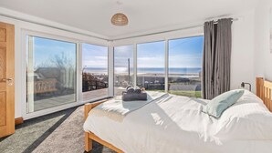Une chambre avec un grand lit, une vue sur la plage et une porte-fenêtre coulissante.