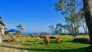 A grassy outdoor area with a stone wall, a table with chairs, and a blue umbrella. - Villa ile vierge-Crozon Nature, sea, listed site (Crozon)