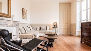 A spacious room with a chaise lounge, a sofa, a wooden coffee table, and a fireplace.