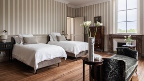 A room with two beds, a fireplace, and a large window.
