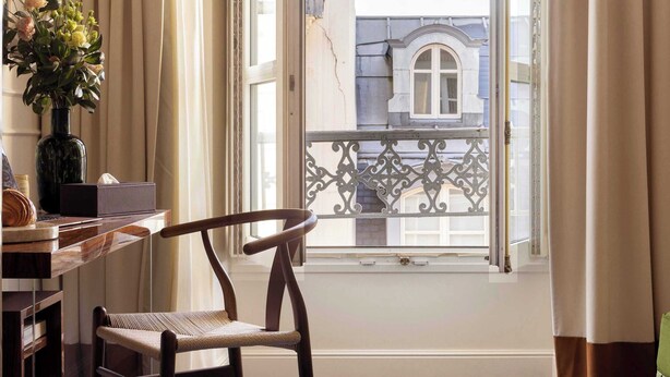 A room with a wooden chair, a desk, and a vase with flowers. - Hôtel Palais Bourbon (Paris)