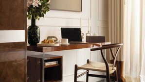 A hotel room with a wooden desk, a laptop, a vase with flowers, a chair, a bedside table, and a green bedspread. - Hôtel Palais Bourbon (Paris)