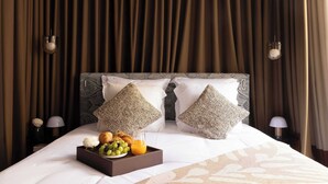 A neatly made bed with two decorative pillows, a tray with fruits and a drink, and a patterned bedspread. - Hôtel Palais Bourbon (Paris)