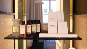 A hotel bathroom vanity with a shaving kit, shower cap, and various toiletries. - Hôtel Palais Bourbon (Paris)