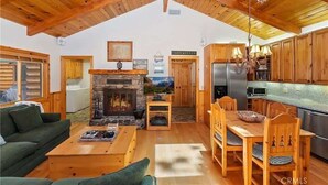 Un acogedor interior de cabaña con chimenea de piedra, mobiliario de madera y una zona de cocina.
