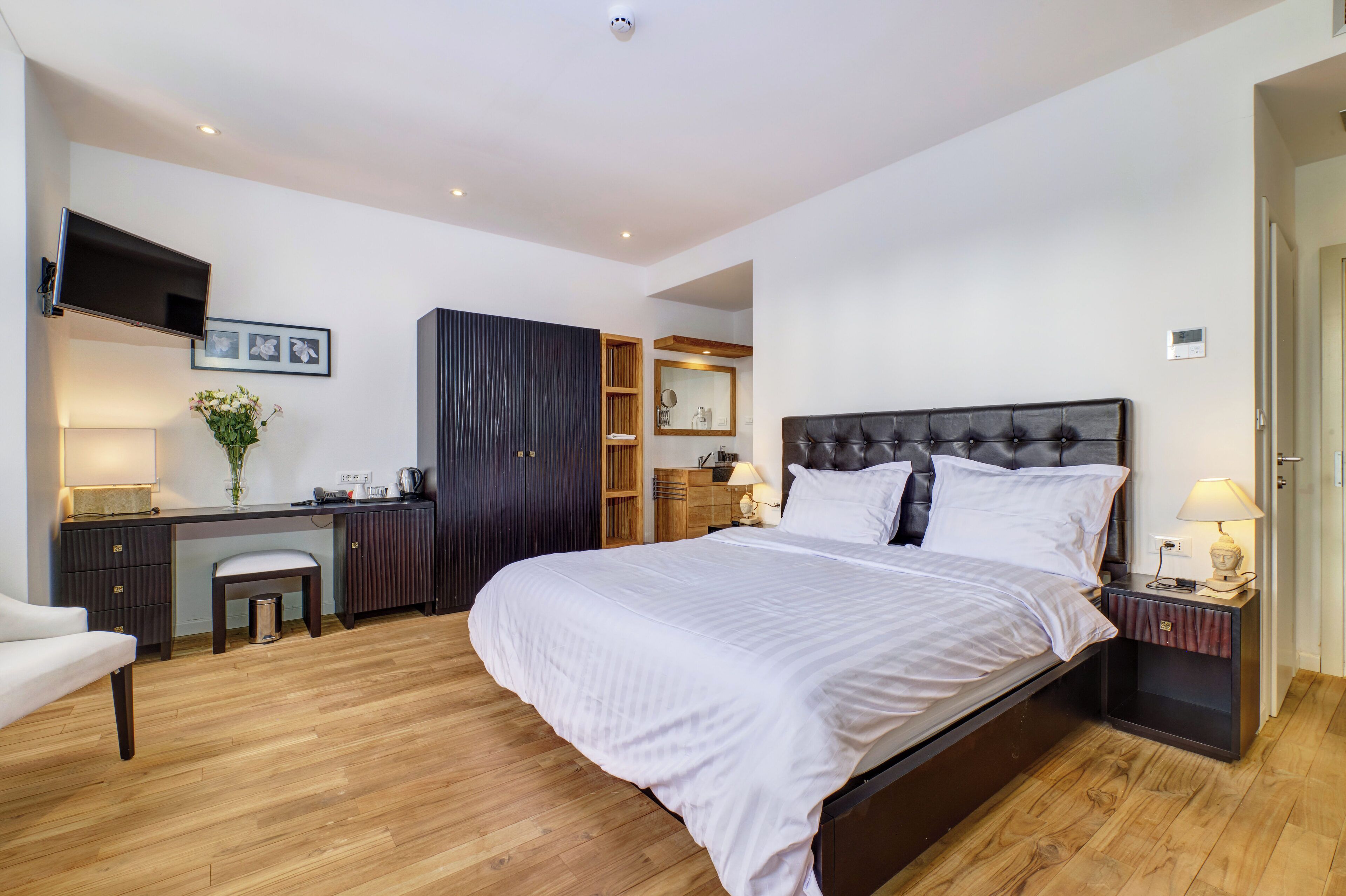 A modern bedroom with a large bed, a desk, and a wardrobe.