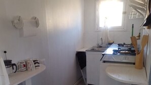 Una cocina compacta con estufa, lavamanos y ventana que proporciona luz natural.