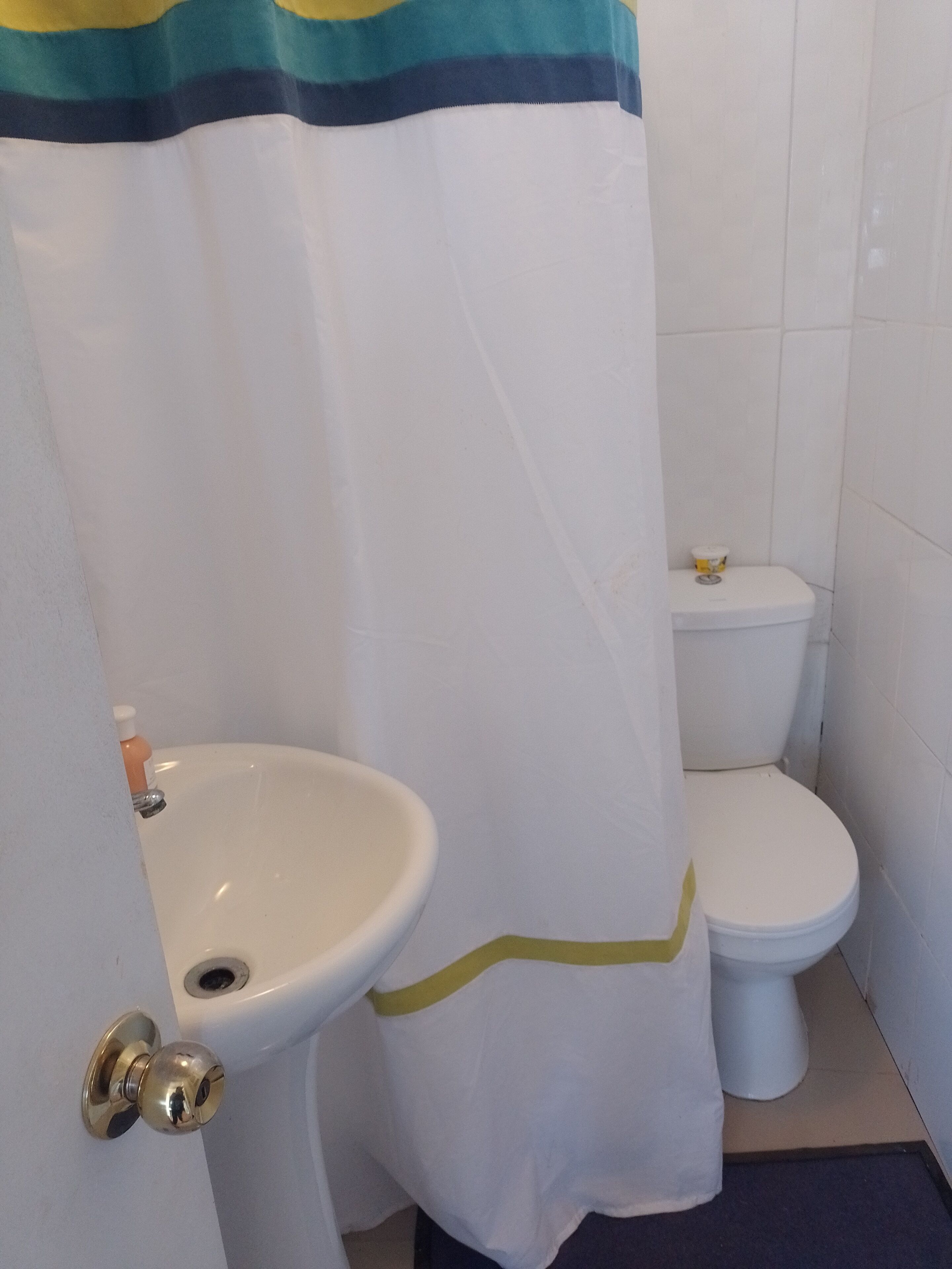 A bathroom with a white sink, toilet, and shower curtain.