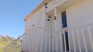Un edificio blanco con un porche, dos faroles y una puerta con un ventanal.