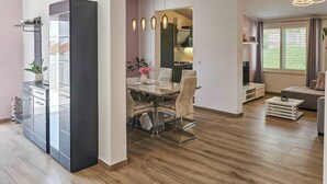 Ein modernes Wohnzimmer mit Essbereich, Holzboden und einem großen Schrank.