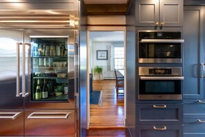 A kitchen with stainless steel appliances, wooden flooring, and a view into a dining area.