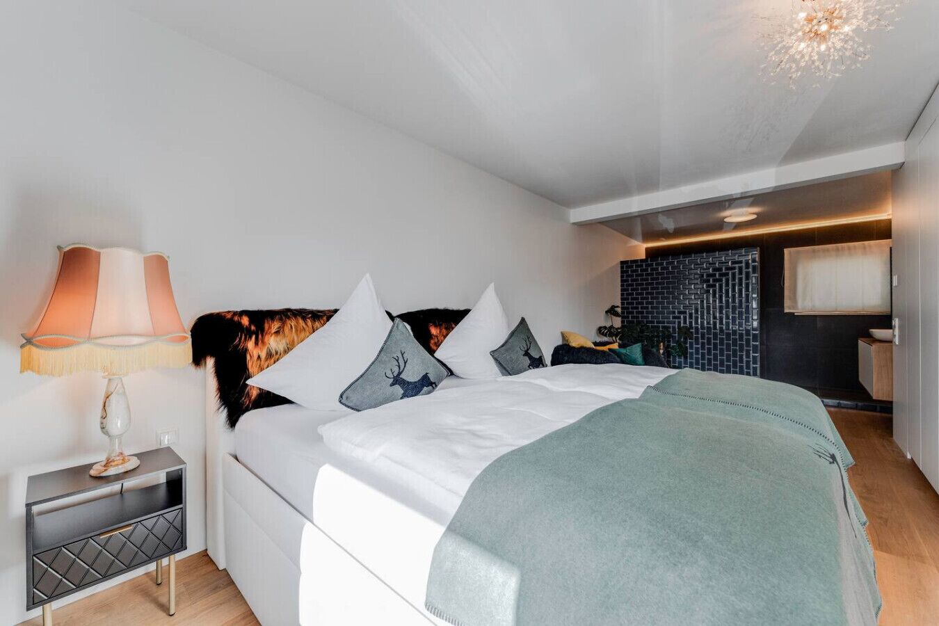 Un dormitorio moderno con cama, mesita de noche, lámpara y estante en la pared.