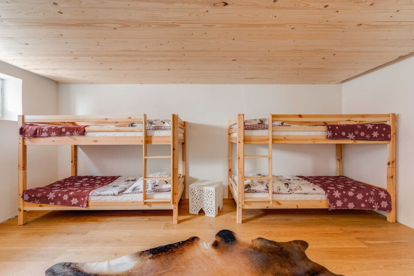 Quarto com duas camas beliche, uma mesinha e um tapete de pele no chão.