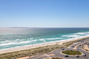 A coastal road with a beach on one side and a clear sky above. - Horizon Haven with stunning view by HMH (Cape Town)