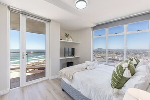 A bedroom with a balcony, a bed, a TV, and a view of the ocean. - Horizon Haven with stunning view by HMH (Cape Town)
