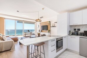 A modern kitchen with a central island, a dining area with a view, and a living space with a sofa. - Horizon Haven with stunning view by HMH (Cape Town)